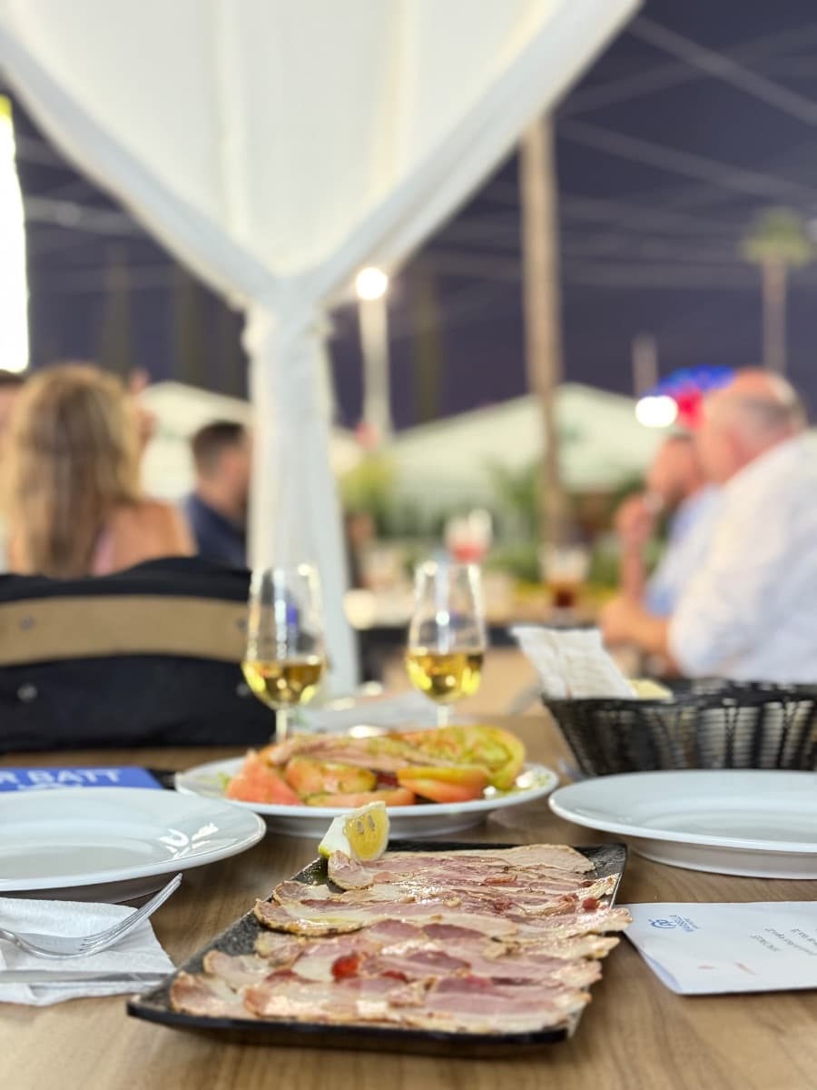 Feria de San Pedro 2025, 15 oct — tapas y copas en mesa de caseta con vistas al recinto, gastronomía y feria nocturna en Marbella.